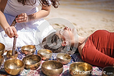 Woman playing a singing bowls also known as Tibetan Singing Bowls, Himalayan bowls. Making sound massage. Stock Photo