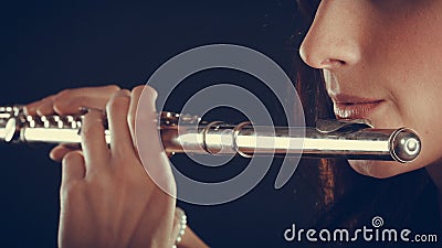 Woman playing transverse flute on black. Stock Photo