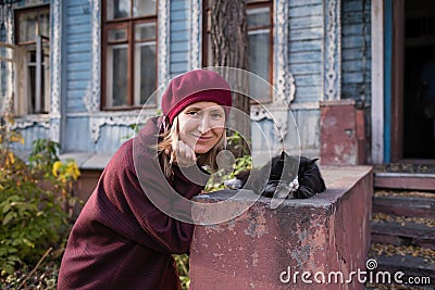 A woman plays with a cat on the porch of an vintage country house Stock Photo