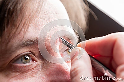 Woman plucking eyebrows with tweezers. Stock Photo