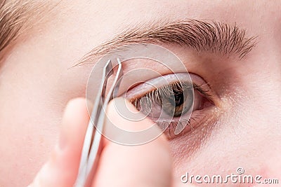 Woman plucking eyebrows with tweezers. Stock Photo