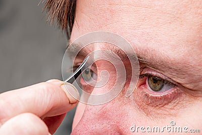 Woman plucking eyebrows with tweezers. Stock Photo