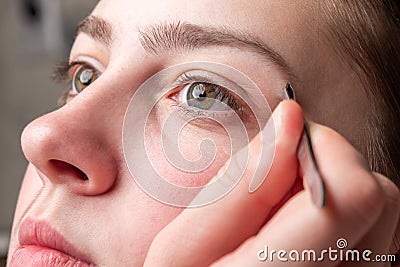 Woman plucking eyebrows with tweezers. Stock Photo