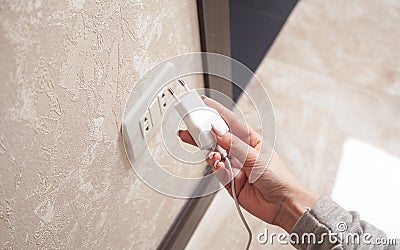 Woman plugs the phone charger into the socket Stock Photo