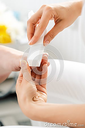 Woman podiatrist polishing nail of man during pedicure Stock Photo