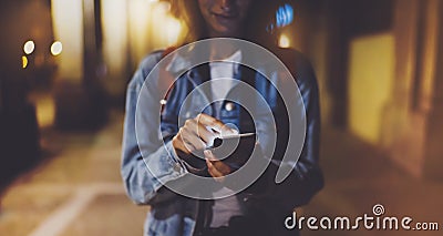 Woman pointing finger on blank screen smartphone on background bokeh light in night atmospheric city, blogger hipster using in han Stock Photo