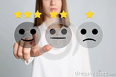 Woman pointing at virtual emoticon to give feedback on light grey, closeup Stock Photo