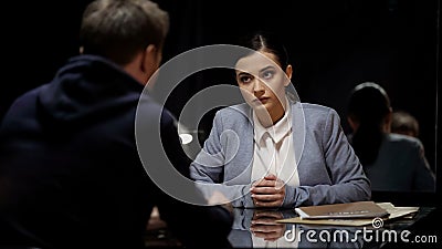 Woman police officer interrogating male suspect in dark room, mistrust, equality Stock Photo
