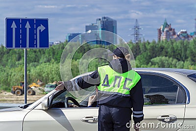 A woman police officer talking to the driver of the car. Rear view Editorial Stock Photo