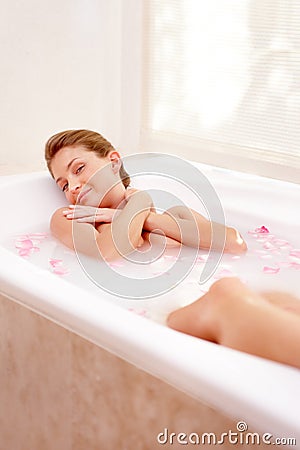Woman portrait, rose and milk bath with flower petals and luxury bathroom treatment. Beauty body care, cleaning and Stock Photo