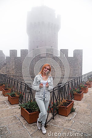 Woman portrait. wearing jeans jacket. Fortification on top of the mountain, old castle on background. Journey. Mystical atmosphere Stock Photo