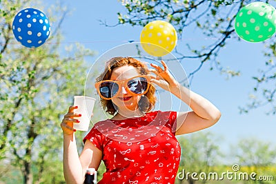 Woman posing in red dress and big funny sun glasses on garden party - summer picnic Stock Photo