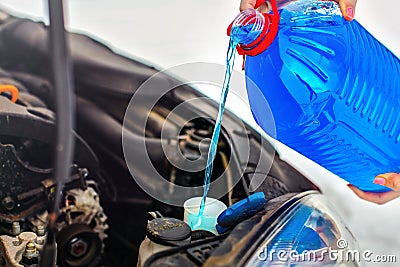 Woman pouring antifreeze car screen wash liquid into dirty car Stock Photo