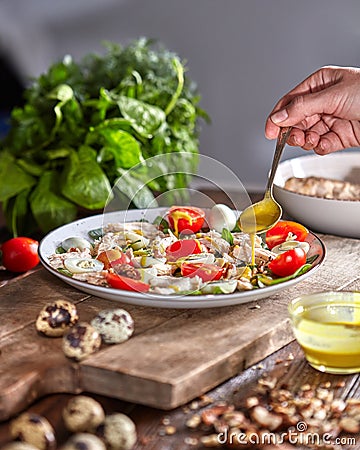 Woman pouring freshly cooked salad mustard sauce on a wooden board. Natural organic dieting food. Stock Photo