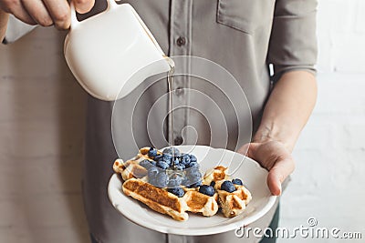 Woman pouring maple syrup on tasty waffles Stock Photo