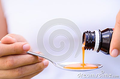 Woman pouring medication or antipyretic syrup from bottle Stock Photo