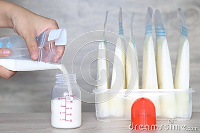 Woman pouring milk in to bottles for new baby on wooden table Editorial Stock Photo