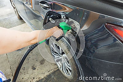 Woman pours fuel into the tank of a black car on gasoline station. Transportation concept. Stock Photo