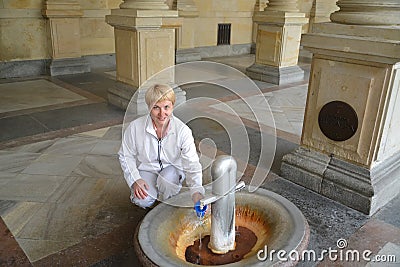 The woman pours water from a mineral source in Karlovy Vary Stock Photo