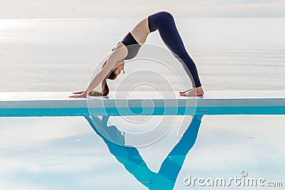 Woman practice yoga Downward Facing dog or yoga Adho Mukha Svanasana pose meditation summer vacation on the pool Stock Photo