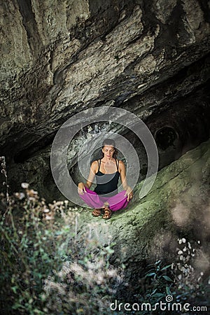 Woman practice yoga meditation in small cave Stock Photo