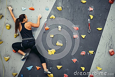 Woman practicing rock climbing on artificial wall indoors. Active lifestyle and bouldering concept. Stock Photo