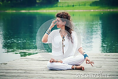 Woman practicing yoga breathing technique by the lake Stock Photo