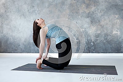 Woman practicing yoga, doing Ushtrasana, Camel Pose, at studio full length. Stock Photo