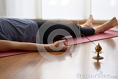 Woman practicing yoga, lying in yoga nidra pose, exercise in Shavasana, exercises, work, rest after practice, female hand. Healthy Stock Photo