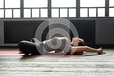 Woman practicing yoga in Reclined Butterfly exercise, supta baddha konasana Stock Photo