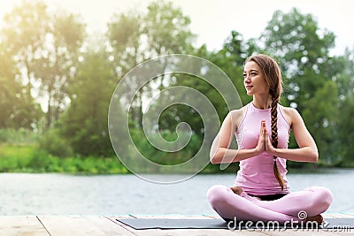 Woman is practicing yoga near the river. Meditation in nature. Copy space Stock Photo