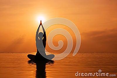 Woman practicing yoga, silhouette on the beach at sunset Stock Photo