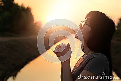 Woman praying with hands together on nature sunset Stock Photo