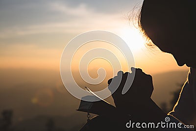 Woman praying in the morning on the sunrise background. Christianity concept. Pray background. Faith hope love concept Stock Photo