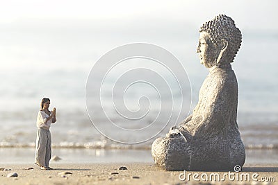 Woman prays meditating in front of the Buddha statue Stock Photo