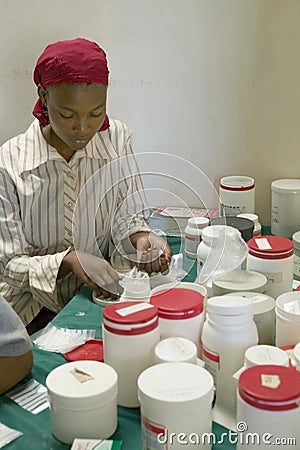 A woman prepares AIDS pills at Pepo La Tumaini Jangwani, HIV/AIDS Community Rehabilitation Program, Orphanage & Clinic. Pepo La T Editorial Stock Photo