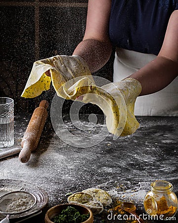 A woman prepares a thin yellow dough for spaghetti. Stock Photo