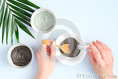 Woman preparing cosmetic clay on pastel blue background. Natural organic SPA facial mask. Flat lay, top view. Face skin care and Stock Photo