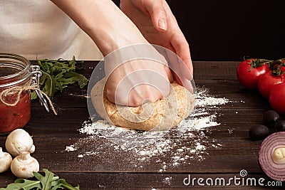 Woman preparing dough for pizza. Hands kneading dough on the wooden table Stock Photo