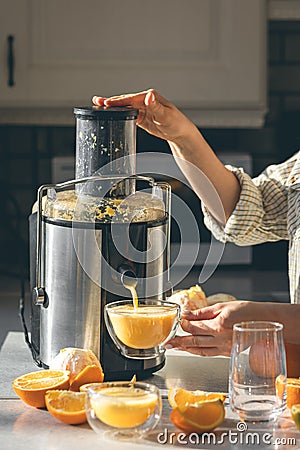 Woman preparing fresh orange juice for breakfast in kitchen. Stock Photo