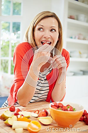 Woman Preparing Fruit Salad In Kitchen Stock Photo