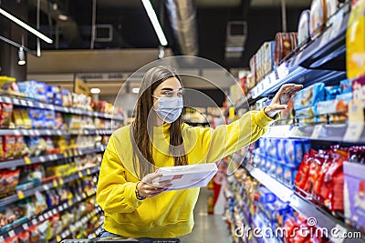 Woman preparing for pathogen virus pandemic spread quarantine.Choosing nonperishable food essentials.Budget buying at a supply Stock Photo
