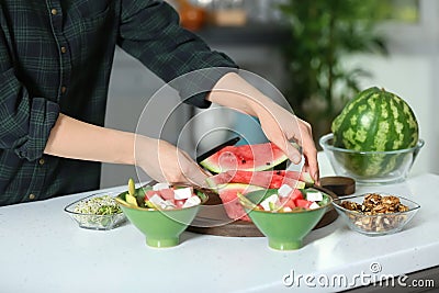 Woman preparing tasty salad with watermelon in kitchen Stock Photo