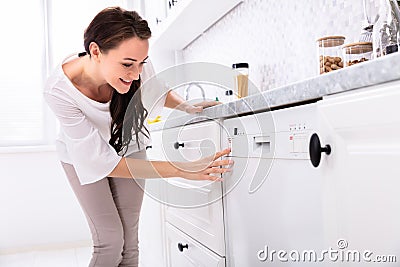 Woman Pressing Button Of Dishwasher Stock Photo