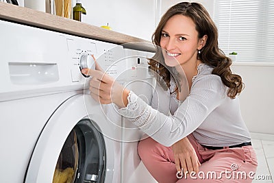 Woman Pressing Button Of Washing Machine Stock Photo