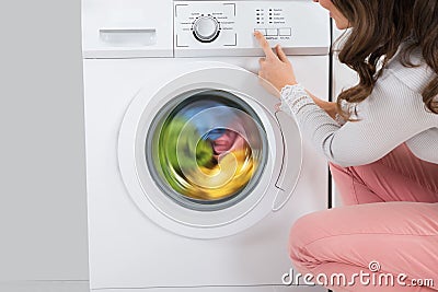 Woman Pressing Button Of Washing Machine Stock Photo