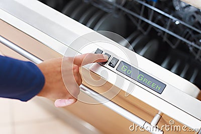 Woman pressing energy saver button on dishwasher Stock Photo