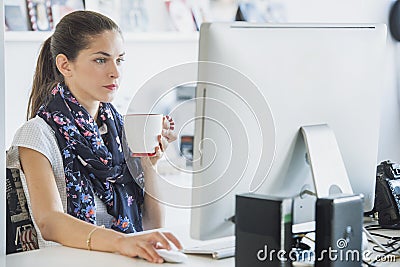 Woman professional is using a computer drinking a beverage Stock Photo