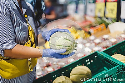 Woman in protective gloves buys melon in a supermarket Stock Photo