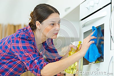 woman in protective gloves cleaning oven Stock Photo